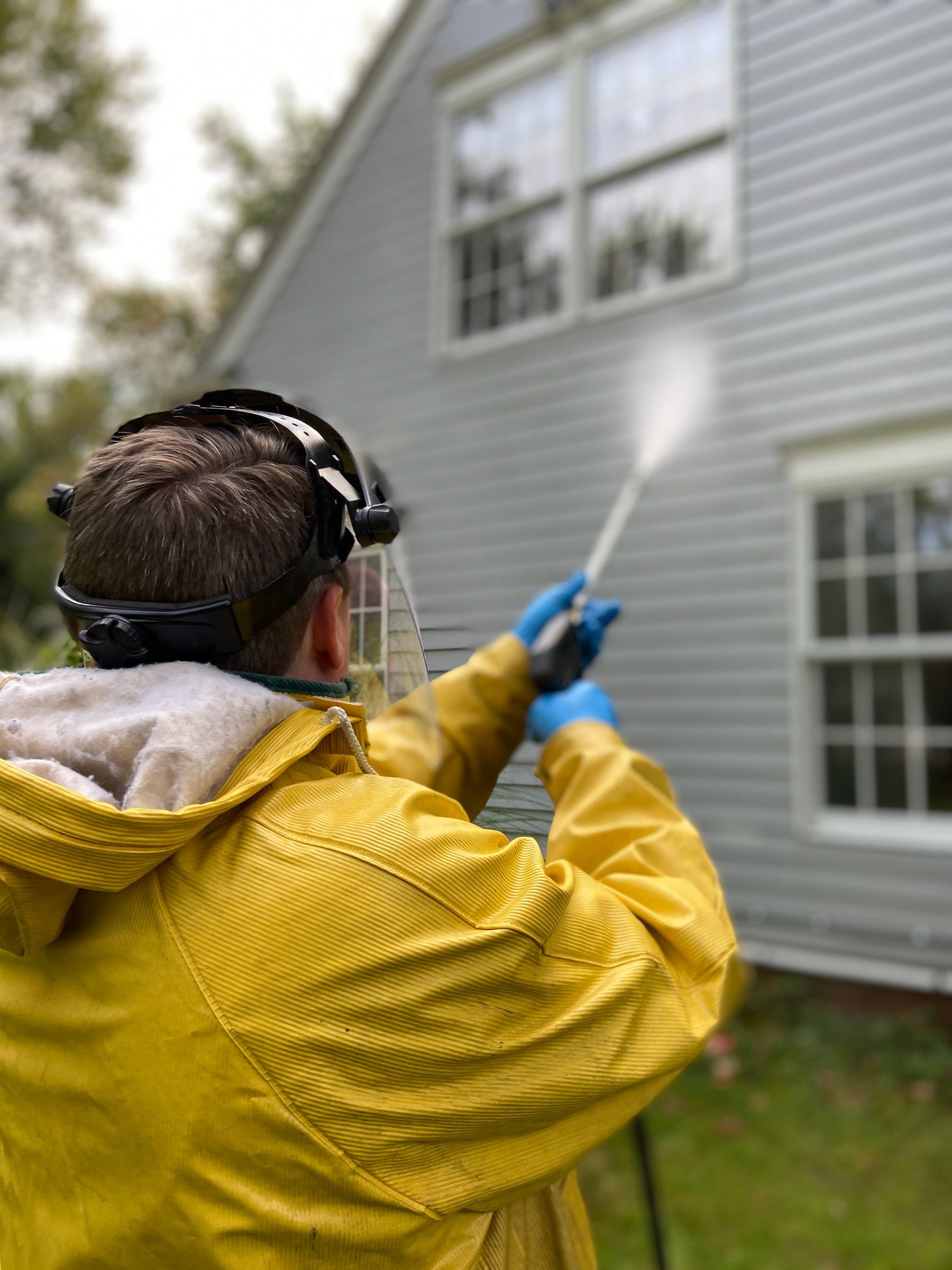 Professional cleaning the siding of a home with pressure-washing equipment